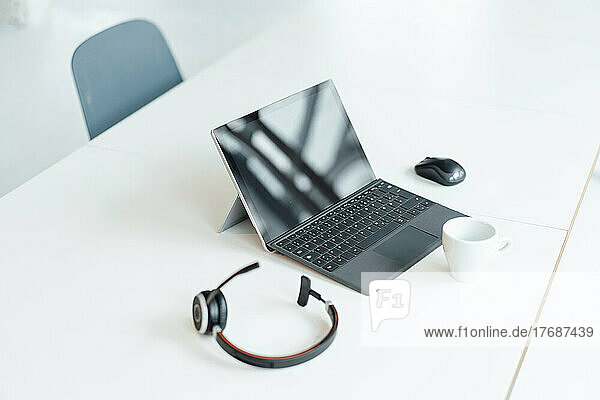 Tablet PC with headset and coffee cup on white desk at office