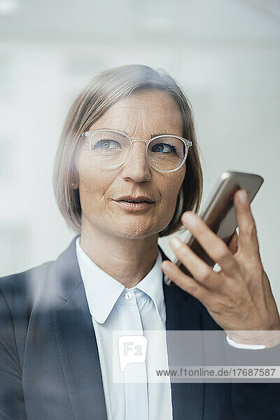 Businesswoman wearing eyeglasses talking on mobile phone speaker