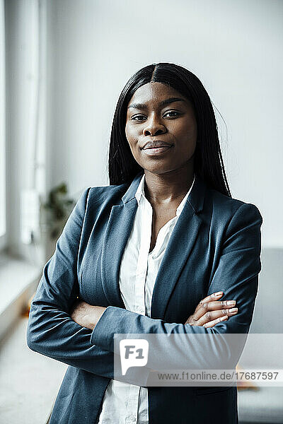 Confident businesswoman standing with arms crossed in office