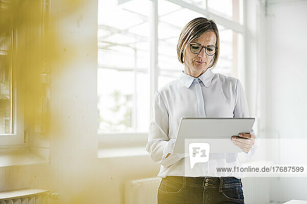 Businesswoman using tablet PC standing in front of window