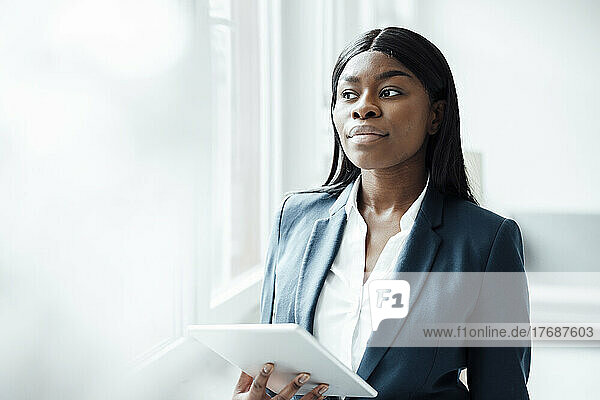 Businesswoman with tablet PC standing in office
