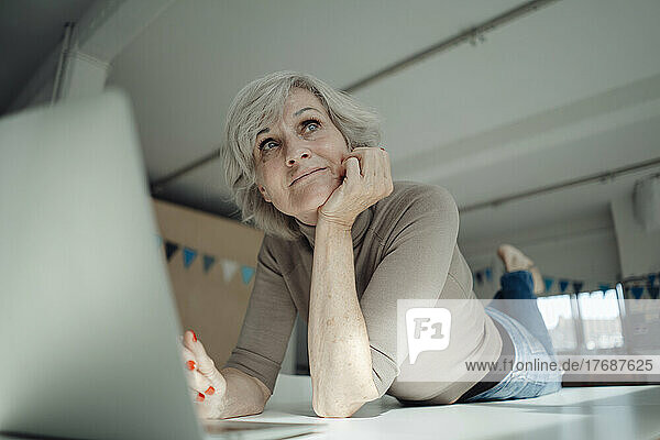 Geschäftsfrau mit Laptop liegt auf dem Schreibtisch im Büro