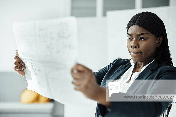 Young architect analyzing blueprint at office