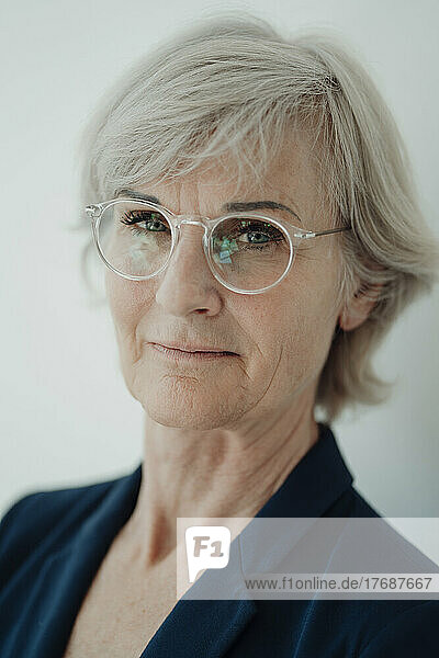 Senior businesswoman wearing eyeglasses against white background