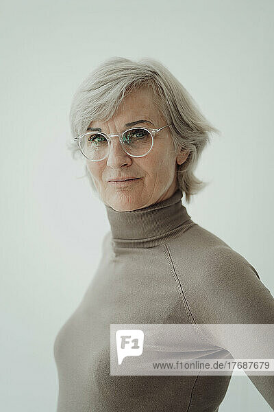 Senior woman wearing eyeglasses standing against white background