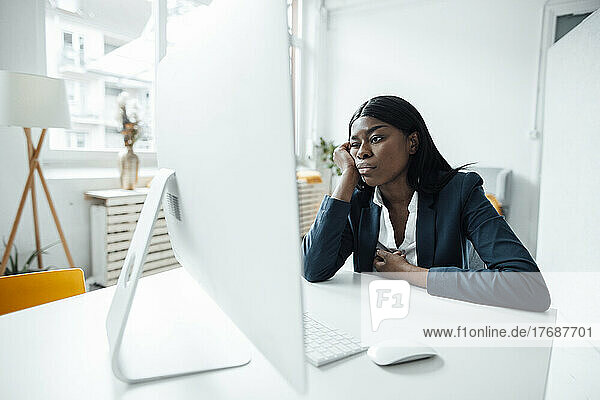 Geschäftsfrau mit Kopf in der Hand und Blick auf den Desktop-PC