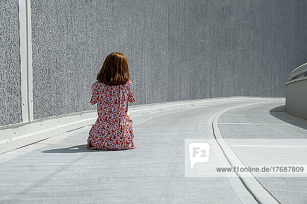 Sad lonely woman sitting on footpath