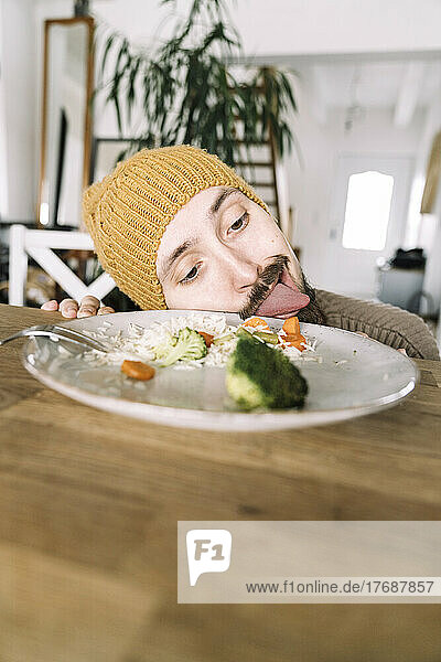Hungriger Mann leckt Teller mit Brokkoli