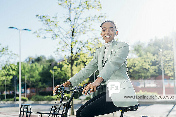 Young businesswoman riding electric bicycle on street