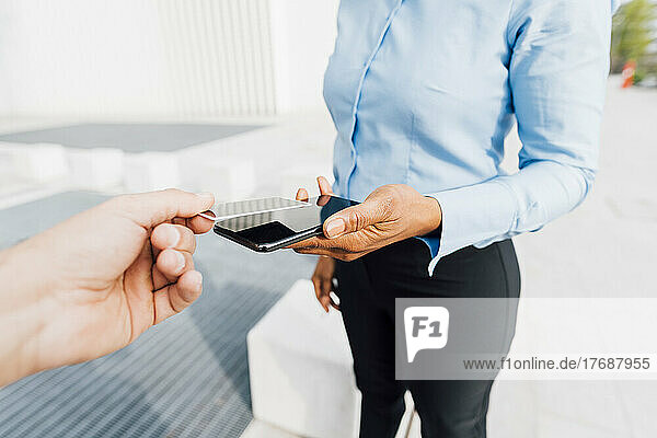 Hand eines Mannes mit Kreditkarte und der Tap-to-Pay-Methode bei einem Freiberufler