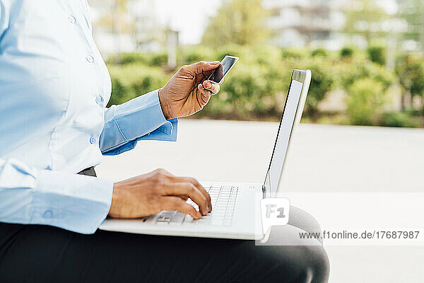 Businesswoman holding credit card doing online shopping through laptop
