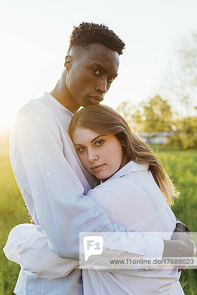 Multiracial young couple hugging each other in nature on sunny day