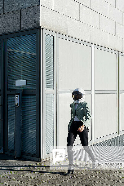 Businesswoman with space helmet walking by office building