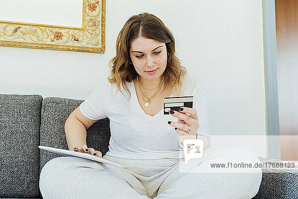 Lächelnde junge Frau  die per Kreditkarte auf einem Tablet-PC bezahlt