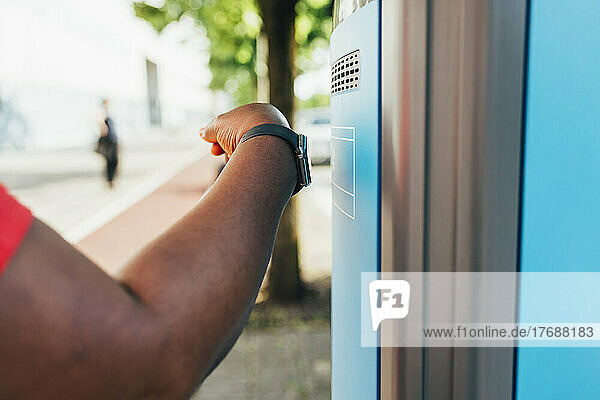 Hand einer Frau mit Smartwatch  die die Bezahlmethode „Tap to pay“ am Fahrkartenautomaten nutzt