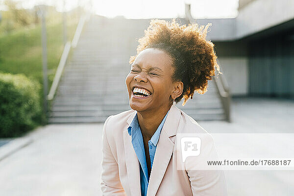 Afro businesswoman laughing in front of staircase