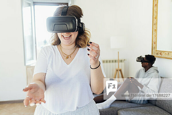 Cheerful woman wearing virtual reality simulator enjoying at home