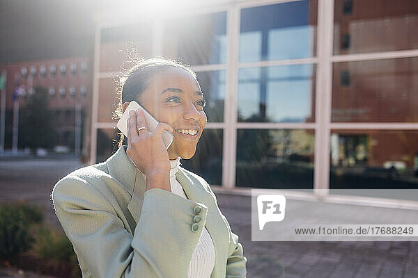 Happy businesswoman talking over mobile phone on sunny day