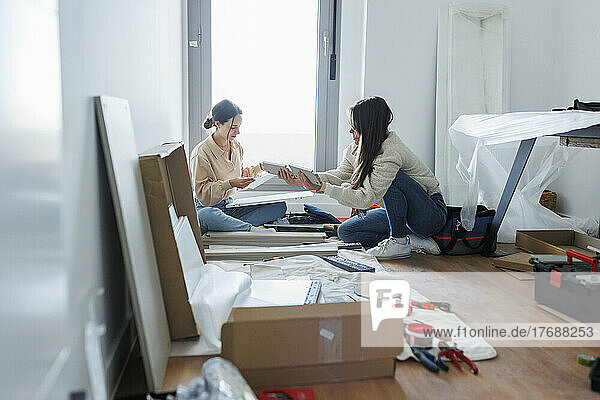 Young lesbian couple installing new furniture at home
