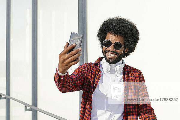 Glücklicher Mann mit Sonnenbrille  der ein Selfie mit dem Smartphone macht