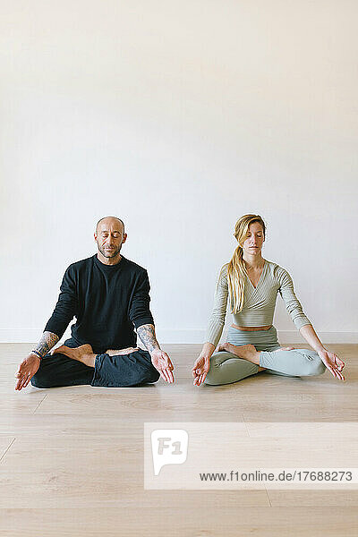 Friends practicing lotus position with eyes closed at yoga class