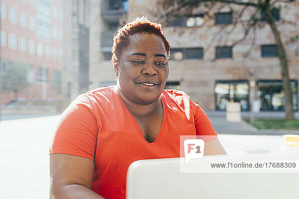 Smiling woman using laptop on sunny day