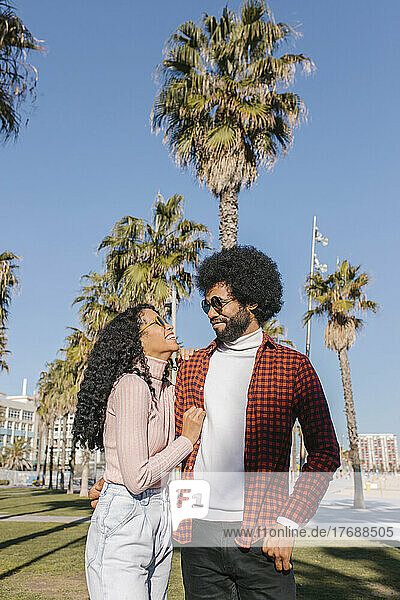 Happy couple standing in front of palm trees on sunny day