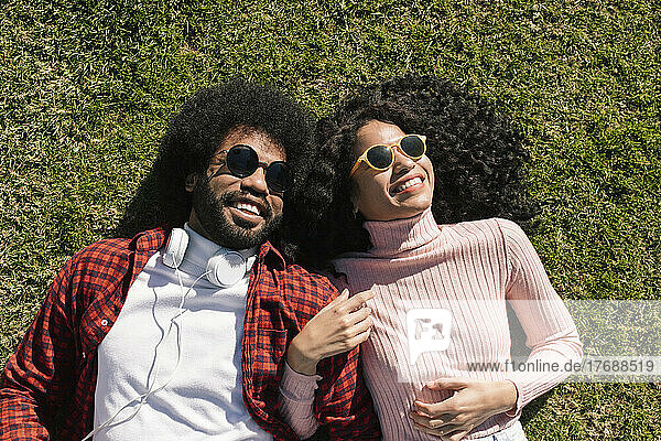 Happy couple wearing sunglasses lying on grass