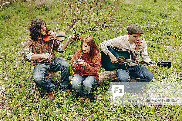 Künstler  die Musikinstrumente üben  sitzen auf dem Baumstammfeld