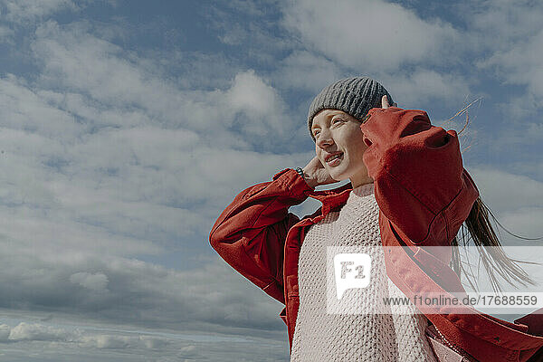 Young woman adjusting knit hat on sunny day