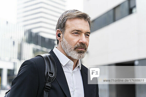 Reifer Geschäftsmann trägt kabellose In-Ear-Kopfhörer