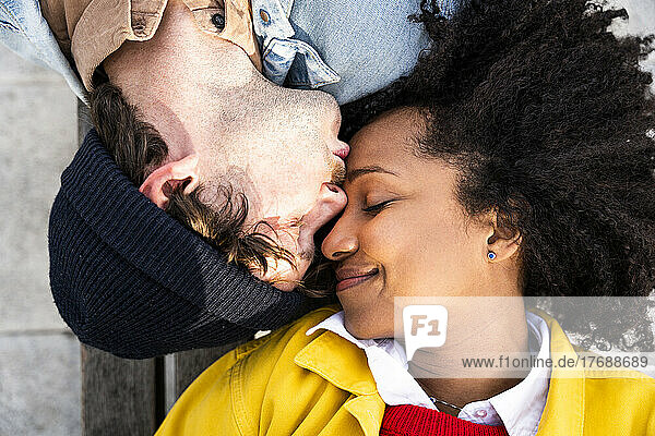 Man with eyes closed kissing girlfriend on forehead
