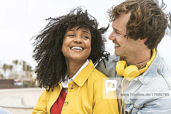 Happy man wearing headphones looking at cheerful girlfriend