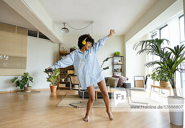 Happy woman with arms outstretched enjoying music at home