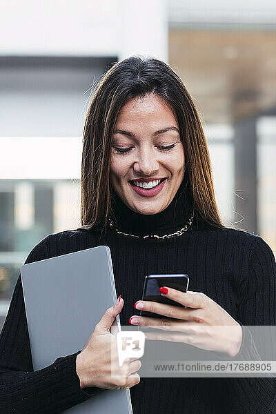 Smiling young businesswoman with brown hair using smart phone