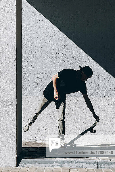 Mann fährt Skateboard vor der Wand