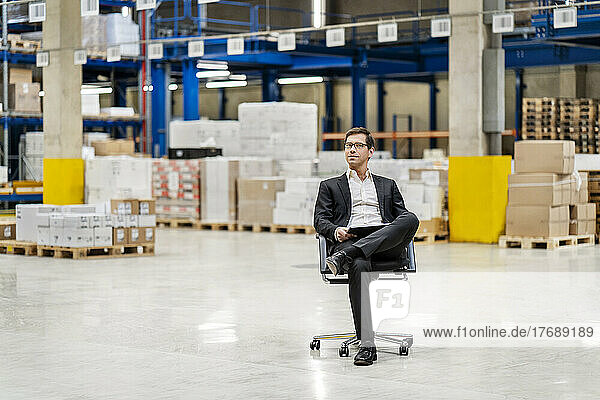 Confident businessman sitting on chair at warehouse