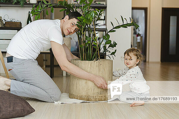Father and daughter holding potted plant in living room at home