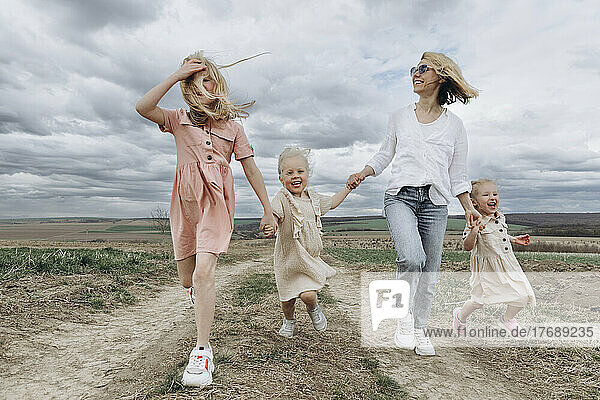 Excited daughters running with mother in agricultural field