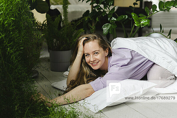 Happy woman lying by houseplants at home