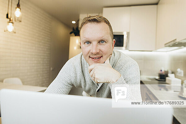 Businessman with laptop in kitchen at home