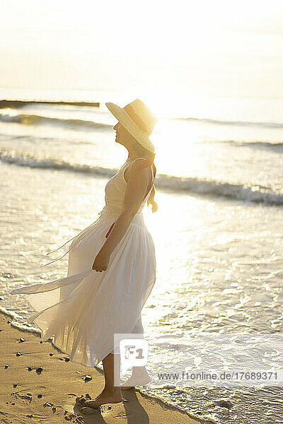 Woman wearing hat standing on shore at beach