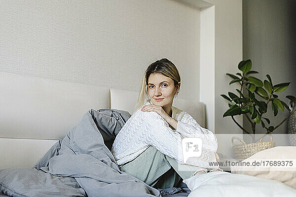 Woman sitting on bed at home in morning