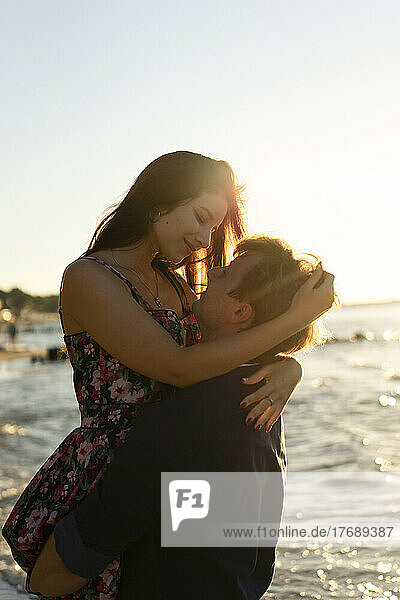 Young couple embracing each other at beach on sunny day
