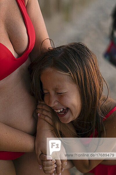 Cheerful daughter laughing with mother at beach