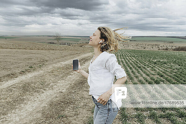 Smiling woman listening music in agricultural field