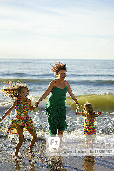 Happy mother and daughters enjoying at beach