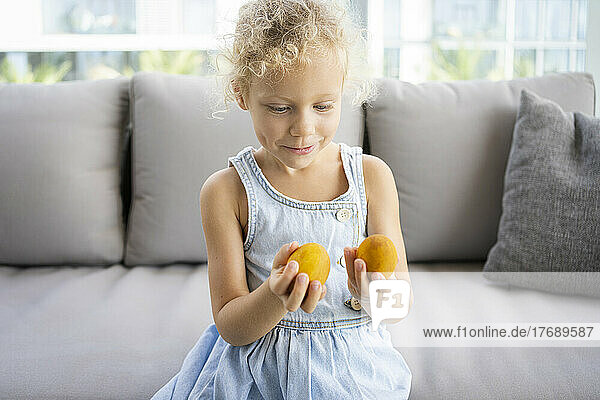 Smiling girl with Easter eggs sitting on sofa at home