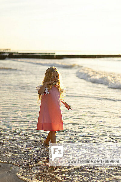 Cute girl with blond hair walking at beach