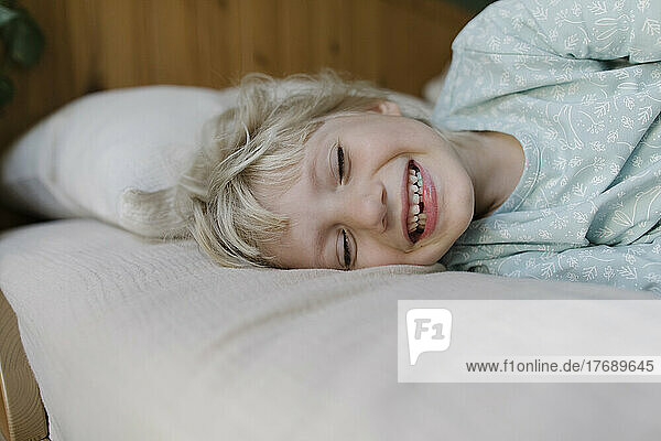 Happy girl with eyes closed lying on bed at home